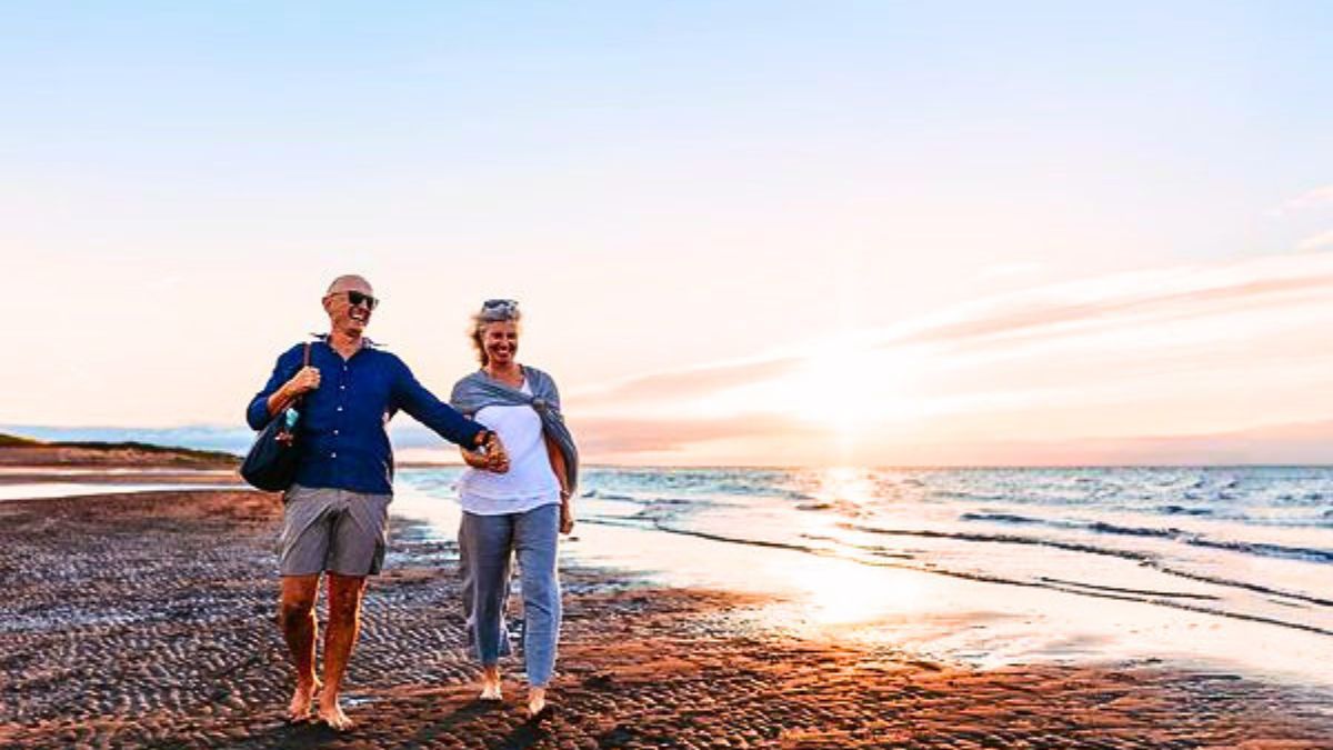 Couple walking along a sandy beach at sunset in Cap-Acadie, New Brunswick