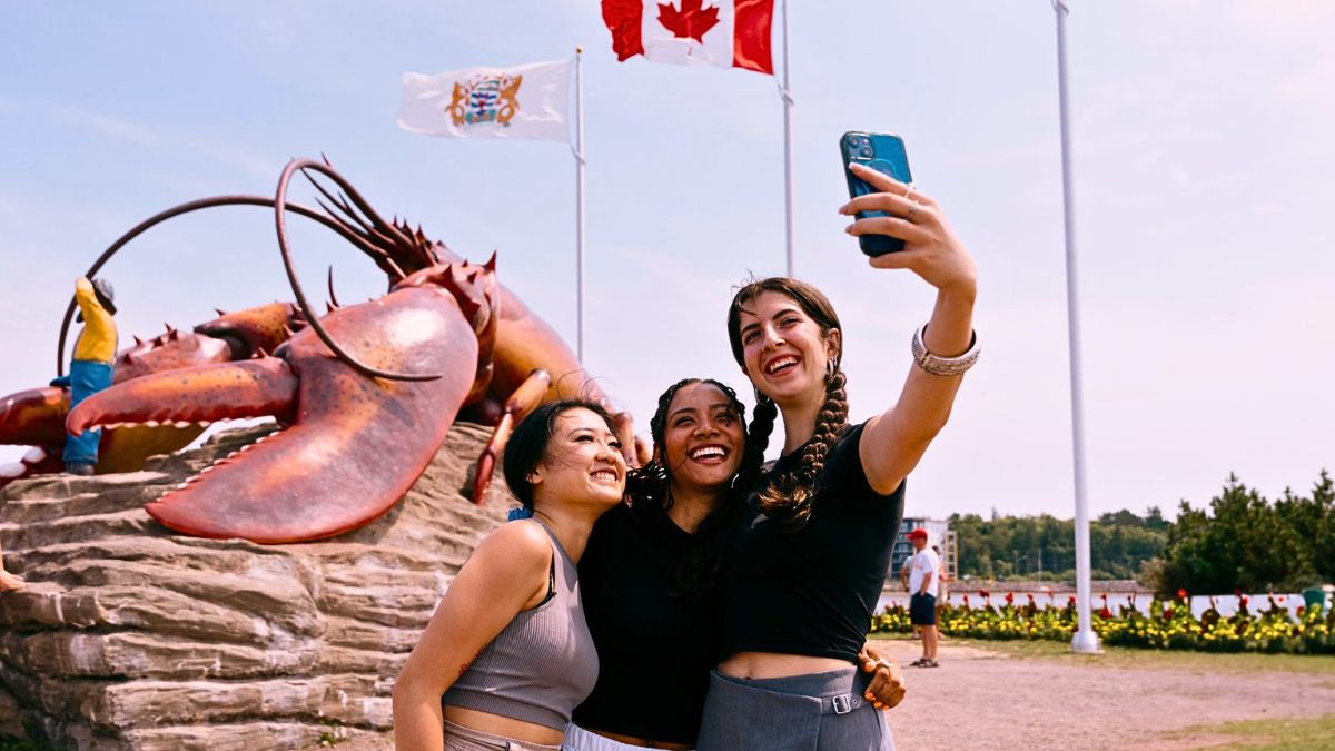 Visitors taking a selfie beside the Giant Lobster attraction in Shediac New Brunswick